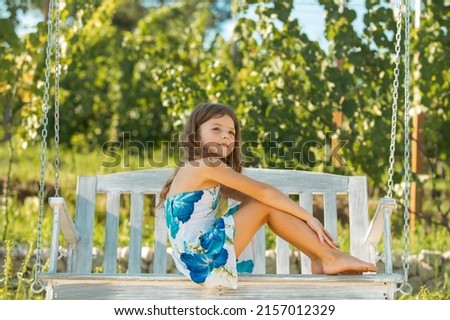 Child swing on backyard. Kid playing oudoor. Happy cute little girl swinging and having fun healthy summer vacation activity. Summer holidays with children.