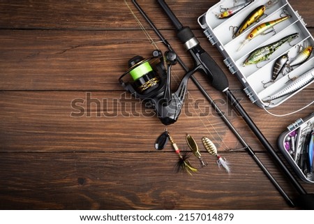 Fishing tackle - fishing spinning rod, hooks and lures on vintage wooden background. Active hobby recreation concept. Top view, flat lay. Copy space for text Royalty-Free Stock Photo #2157014879