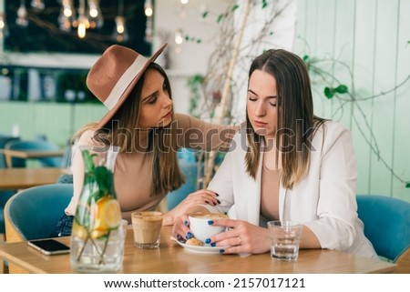 young caucasian woman comforts her friend in cafe during coffee break Royalty-Free Stock Photo #2157017121