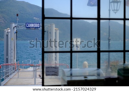 A beautiful shot of a glass door on a ship with a Cannobio sign with green mountains background