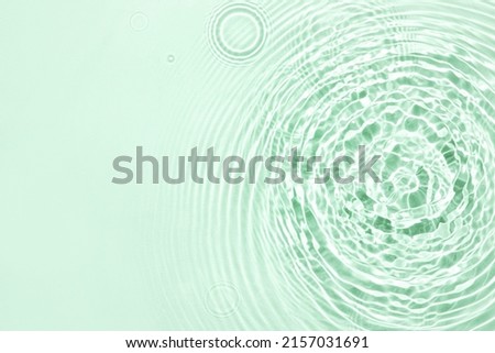 The texture of water on a green background in bright sunlight.