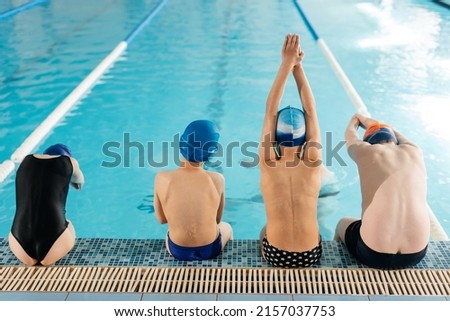 A group of boys and girls train and learn to swim in a modern swimming pool with an instructor. Development of children's sports. Healthy parenting and promotion of children's sports. Royalty-Free Stock Photo #2157037753