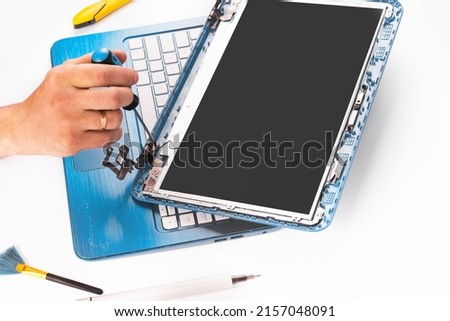 The engineer repairs blue laptop, pc, computer and the screen in the white background. laptop screen replacement. Installs the equipment, cpu. isolated