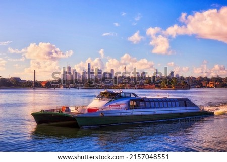 Passenger rivercat ferry on Parramatta river in view of Sydney city CBD landmarks cityscape - public transport on waterway.