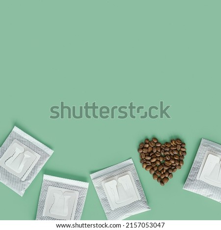 Drip coffee bag and heart from coffee beans, ground coffee for brewing in cup, pack with paper bag drip coffee filter, mint color background, top view, minimal flat lay with copyspace, pastel color Royalty-Free Stock Photo #2157053047
