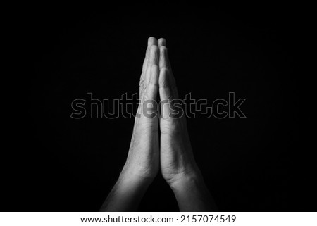 Dramatic black and white image of Folded Hands emoji isolated on black background