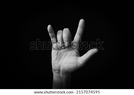 Dramatic black and white image of Love You Gesture emoji isolated on black background