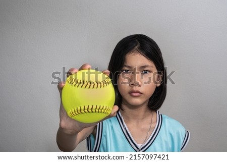 softball girl,Asian girl holding a softball ball,softball ball is out of focus.