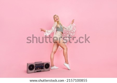 Full size photo of young blond lady dance near boombox wear top cape shorts footwear isolated on pink background