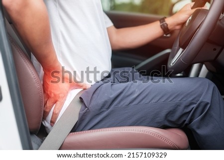 man with his back sprain while driving car long time, back body ache due to Piriformis Syndrome, Low Back Pain and Spinal Compression. Ergonomic and medical concept Royalty-Free Stock Photo #2157109329