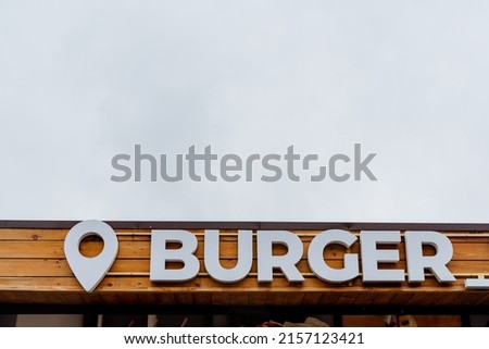 Burger sign on the sky, street restaurant meat food, concept fast fun in town, fast food, white letters inscription wooden background. High quality photo