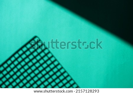 Geometric shadows on a blue background. The shadow of the lattice. Small squares. Abstract background. The texture of the paper.