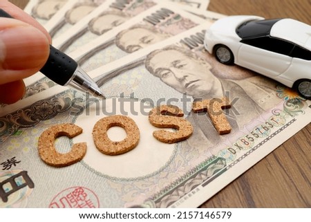 A car and several Japanese banknotes. This is a picture about the cost of an automobile.
