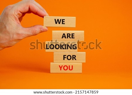 We are looking for you symbol. Wooden blocks with words We are looking for you. Businessman hand. Beautiful orange background, copy space. Business, we are looking for you concept.