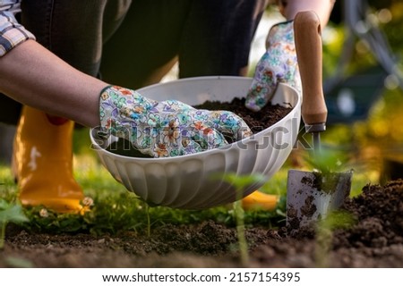 Eco friendly gardening. Woman improving garden bed soil for planting, fertilizing with compost. Organic matter soil amendment. Royalty-Free Stock Photo #2157154395