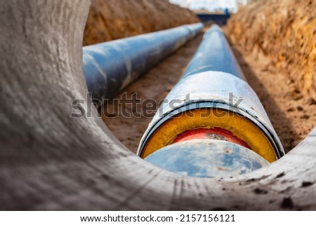 Insulated pipe. Large metal pipes with a plastic sheath laid in a trench. Modern pipeline for supplying hot water and heating to a residential area Royalty-Free Stock Photo #2157156121