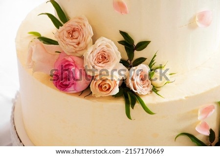 white wedding cake decorated with mastic flowers on a white table. Picture for the menu or catalog of confectionery. wedding celebration concept