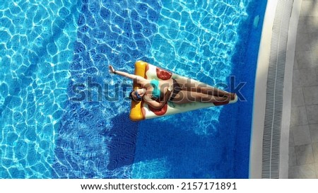 A girl on an inflatable mattress swims in the pool, plus size woman in the pool. Pizza mattress