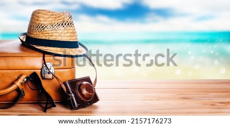 Vintage suitcase, sunglasses and hipster hat wooden deck and blur tropic sea background. Summer paradise cruise travel design layout banner. Tourism, beach, vacation travel destination concept mockup