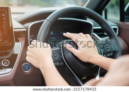 woman driver honking a car during driving on traffic road, hand controlling steering wheel in vehicle. Journey, trip and safety Transportation concepts Royalty-Free Stock Photo #2157178433