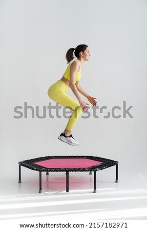 young fitness woman In sportswear jumping on sport trampoline White background Royalty-Free Stock Photo #2157182971