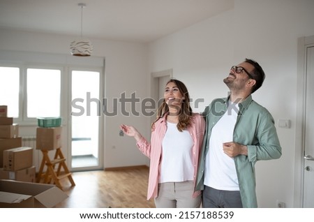 Young smiling couple looks around their new apartment and they look satisfied while the woman holds the keys in her hand Royalty-Free Stock Photo #2157188539