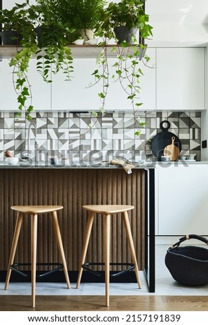 Stylish kitchen interior design with dining space. Workspace with kitchen accessories on the back ground. Creative walls with woode pannels. Minimalistic style an plant love concept. 