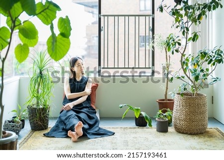 A woman relaxing surrounded by foliage plants in the room Royalty-Free Stock Photo #2157193461