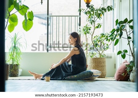 A woman relaxing surrounded by foliage plants in the room Royalty-Free Stock Photo #2157193473
