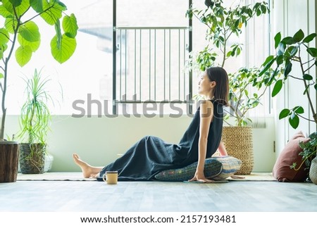 A woman relaxing surrounded by foliage plants in the room Royalty-Free Stock Photo #2157193481