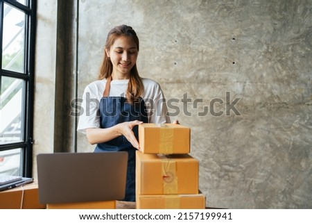 Small business owner concept, Portrait young attractive asian female owner startup business  work happy with box at home prepare parcel delivery in sme supply chain.