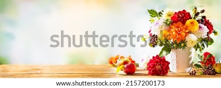 Autumn still life with garden flowers. Beautiful autumnal bouquet in vase, apples and berries on wooden table. Colorful dahlia and chrysanthemum. Royalty-Free Stock Photo #2157200173
