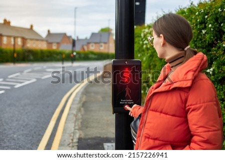 A woman crosses the road by pressing a button at a pedestrian traffic light. A new generation of traffic lights. The concept of a safe city. Traffic rules for children. Royalty-Free Stock Photo #2157226941