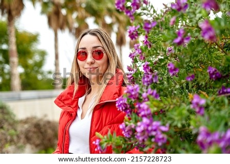 Portrait of a young girl with red glasses looking at camera in the park in spring