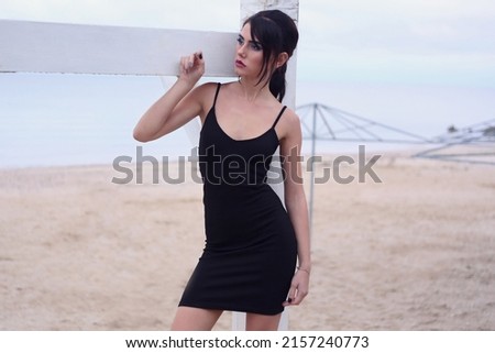 beautiful fashionable girl stands on the seashore of the sia in a drass at the watter