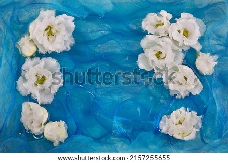 White flowers of eustoma, lisianthus, on a background of blue soft silk fabric
