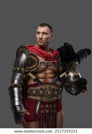 Shot of isolated on grey background roman gladiator holding plumed helmet.