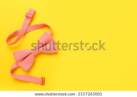 Stylish pink bow tie on yellow background, top view. Space for text