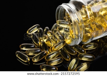 Fish oil capsules in bottle isolated on black background. Healthy Omega 3 Supplement