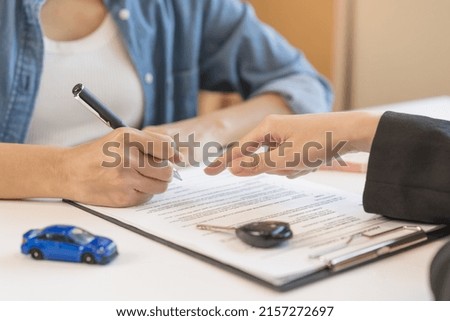 Business car rental company service, hand of agent dealer is pointing to purchase contract of tenant to sign signature on document, new owner after signed rental , vehicle sales agreement.