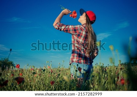 Beautiful girl in poppy field. Young girl with long hair among the blossoming poppy field. concept of freedom and travel. Poppy buds. Gardening