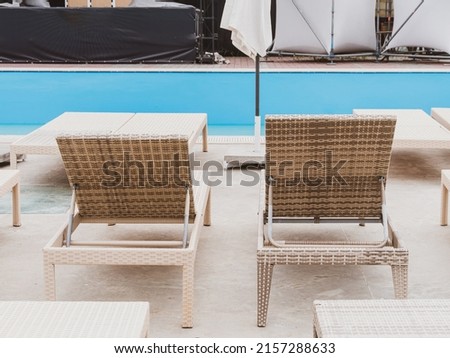 Rattan reclining chaise. Comfortable outdoor patio wicker chaise lounges. Swimming pool backyard resort furniture. Empty chairs in hotel with sunlight on sunny day.