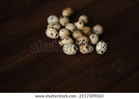 Small quail eggs on brown wooden and white foundations and on a towel, quiet photo