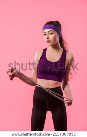 Athletic girl in fashionable sportswear holding jump rope. Sport, healthy lifestyle. Portrait of pretty fitness model