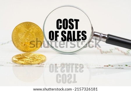 Business and technology concept. There are bitcoins on the chart and there is a magnifying glass with the inscription - COST OF SALES