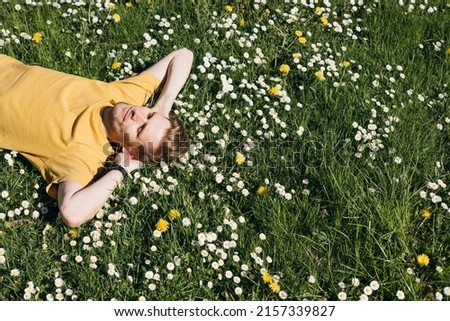 Young man laying in green grass with flowers. People fatigue from work. Summer sleeping and relaxation techniques. Vitamin D sunbathing. Man power nap with eye closed. Rest after work from home Royalty-Free Stock Photo #2157339827