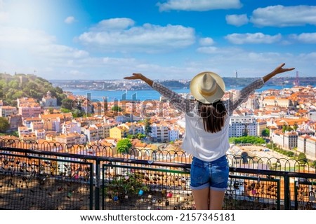 A happy tourist woman overlooks the colorful old town Alfama of Lisbon city, Portugal, and castle Sao Jorge on her sightseeing trip Royalty-Free Stock Photo #2157345181