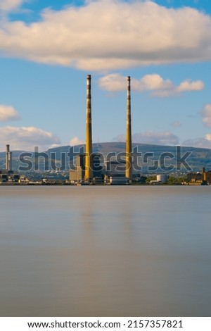 A beautiful view of a lake near a factory in a city under a cloudy sky