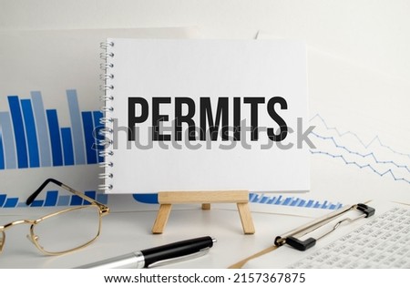white notebook with the text PERMITS. Business concept