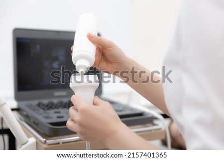 Closeup hands of woman doctor preparing for ultrasound device scan. Gynecologist applies gel on echography. Royalty-Free Stock Photo #2157401365